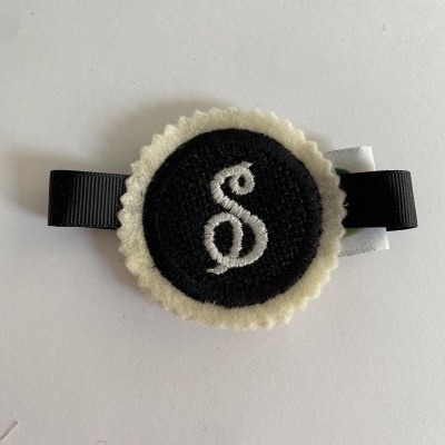 Broche redondo de feltro com símbolo ß bordado e fita preta