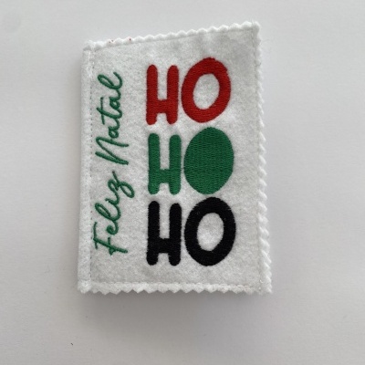 Etiqueta branca em tecido com texto bordado colorido de Natal