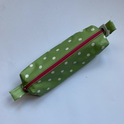 Estojo verde com bolinhas brancas e fecho vermelho