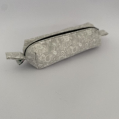 Estojo retangular cinzento claro com padrão floral branco e fecho preto