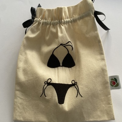 Saco de tecido bege com ilustração de biquíni preto e cordões pretos