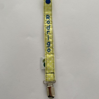 Presilha para chupeta amarela com bolinhas brancas e nome 'Rodrigo' bordado a azul