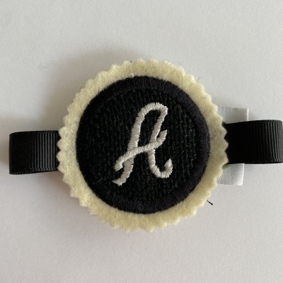 Acessório de feltro com letra A bordada e fita preta e branca