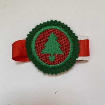 Clip decorativo com fita vermelha e branca e emblema de árvore de Natal verde em fundo vermelho