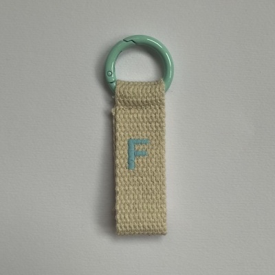 porta-chaves com argola azul claro e tira bege com letra F azul