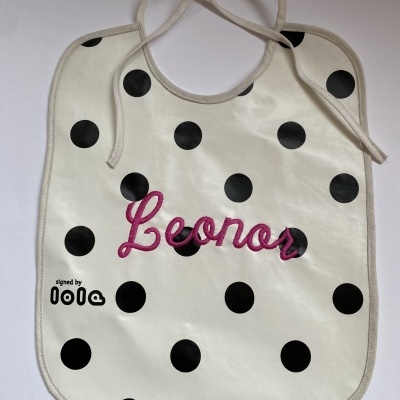 Babete branco com bolinhas pretas e nome Leonor bordado a rosa.