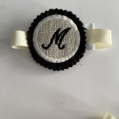 Clip de tecido bordado com letra M e fita creme
