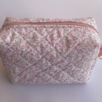 Necessaire acolchoada com padrão floral rosa e verde e fecho de correr cor-de-rosa.