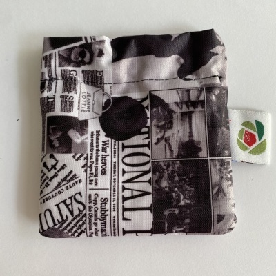 Saco pequeno em tecido com padrão a preto e branco que imita páginas de jornal