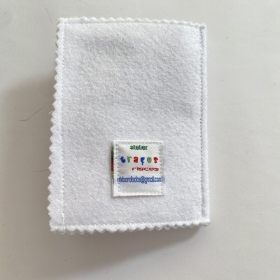 Peça de tecido branco com etiqueta colorida costurada e texto legível