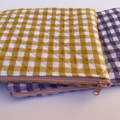 Sacos almofadados xadrez amarelo e roxo com fechos éclair rosa.