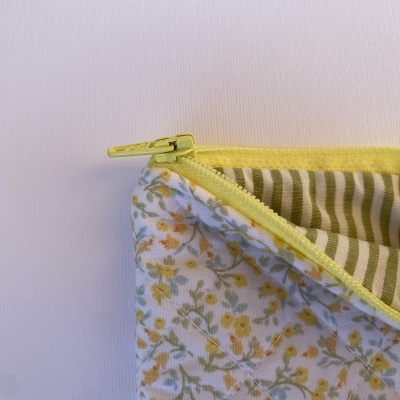 Necessaire de tecido com padrão floral amarelo e verde e fecho amarelo