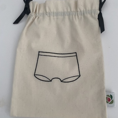 Saco de tecido cru com cordão e laços pretos e desenho preto de cuecas