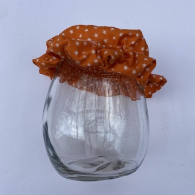 Frasco de vidro com tampa em tecido laranja com estrelas brancas
