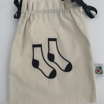 Saco de tecido bege com desenho de meias pretas e cordão preto