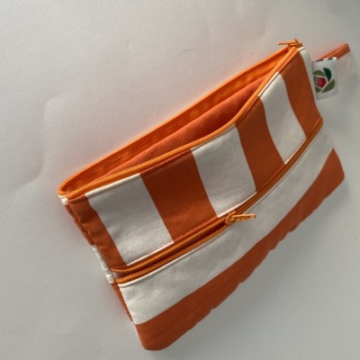 Estojo pequeno de tecido com riscas laranja e branco e fecho laranja.