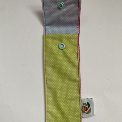 Estojo de tecido azul claro e amarelo com padrão de bolinhas pequenas e etiqueta com rosa