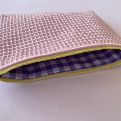 Necessaire rosa com padrão waffle e forro xadrez violeta e branco