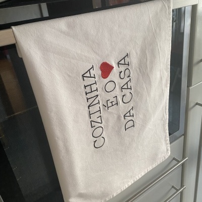 Pano de cozinha branco com bordado texto COZINHA É O coração DA CASA pendurado na cozinha