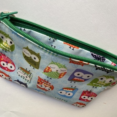 Bolsa pequena de tecido com padrão de corujas coloridas e fecho verde