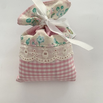 Saco pequeno decorativo em tecido com padrões rosa e branco com flores e renda branca