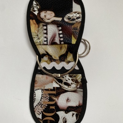 Carteira ou porta-chaves preto com imagens femininas estilizadas em tons castanhos e argolas metálicas