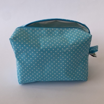 Bolsa azul claro de tecido com bolinhas brancas e fecho de correr