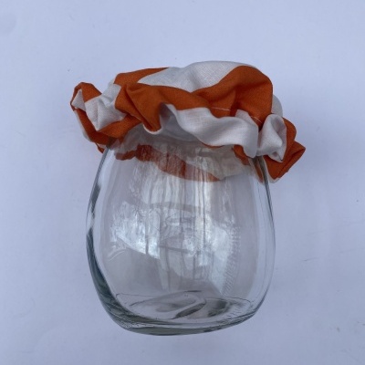 Frasco de vidro com tampa de tecido laranja e branco