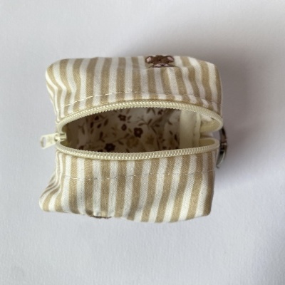 Necessaire pequena riscada bege e branco com abertura de fecho zip