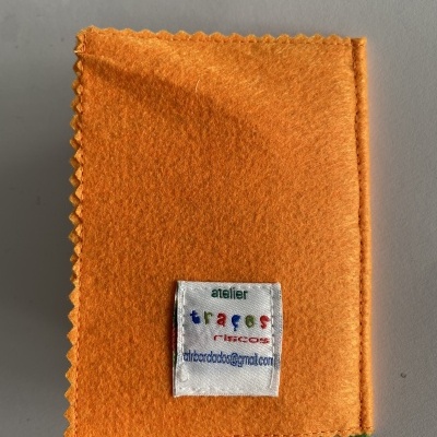 Pano de feltro laranja com etiqueta branca colorida sobre fundo cinza