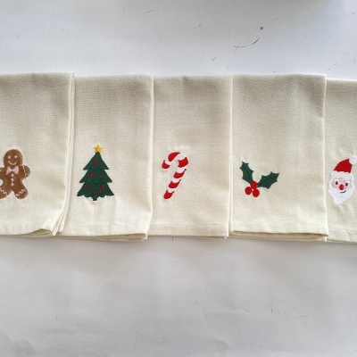 Cinco guardanapos bege com bordados natalícios variados