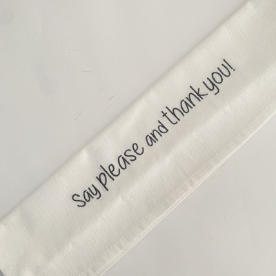 Guardanapo branco de tecido com texto bordado a preto