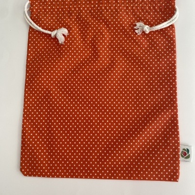 Saco de tecido vermelho com padrão de pontos brancos e cordão branco.