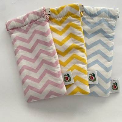 Três bolsas em tecido com padrão zig zag rosa, amarelo e azul com etiquetas em fundo branco