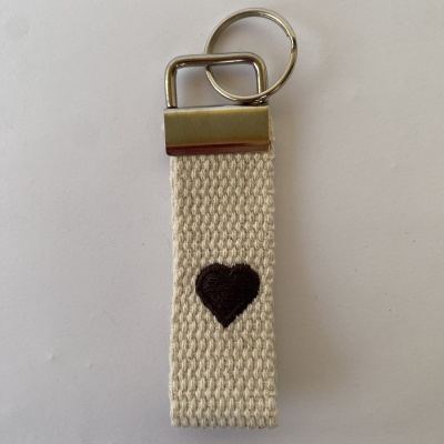 Porta-chaves de tecido bege com coração preto bordado e metal prateado
