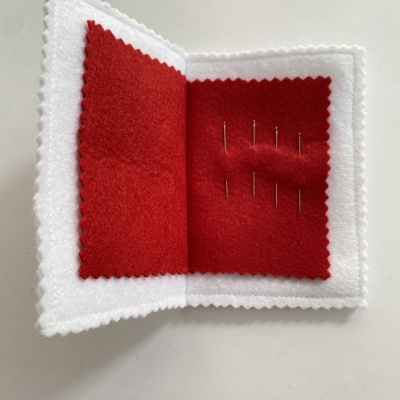 Porta agulhas em feltro branco e vermelho com agulhas.