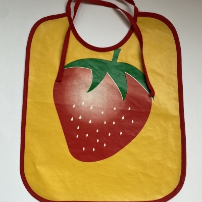 Babete amarelo com bordo vermelho e imagem de morango