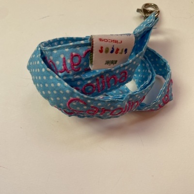 Pulseira azul de tecido com bolinhas brancas e bordado com nome