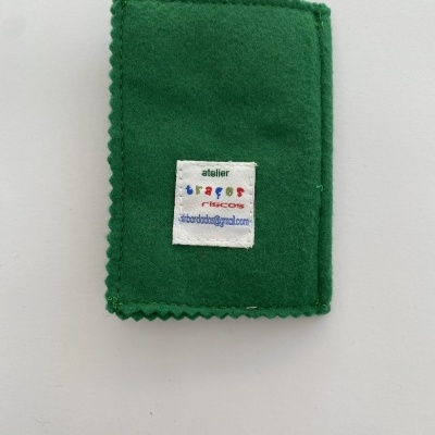 Carteira de tecido verde com etiqueta costurada contendo texto e email.