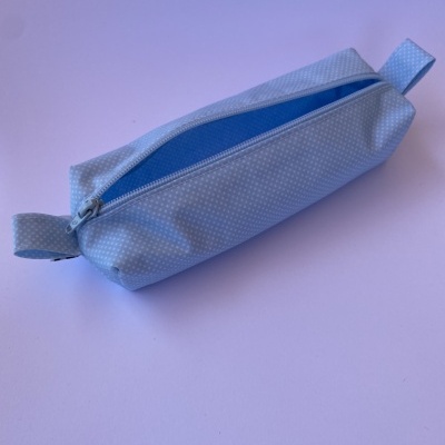 Estojo azul claro com padrões de pontos brancos e fecho de correr azul