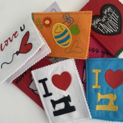 Capas de feltro coloridas com desenhos e textos bordados