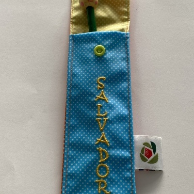 Estojo azul com padrão de poás brancos e caneta com cabeça de boneco