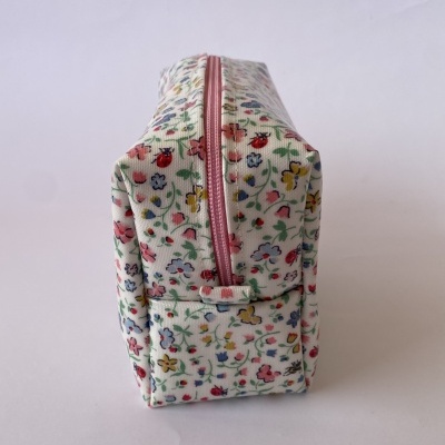 Estojo em tecido com padrão floral e fecho cor-de-rosa