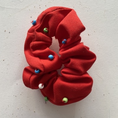 Elástico de cabelo vermelho com contas coloridas sobre fundo branco