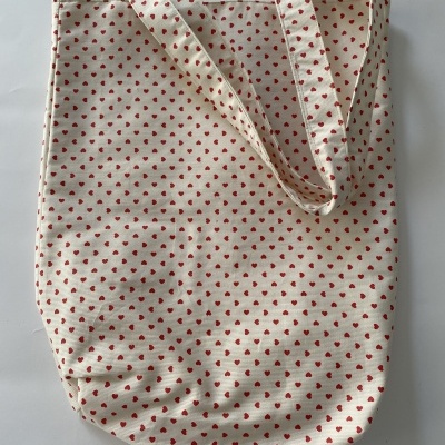 saco de tecido branco com pequenos corações vermelhos e alças largas