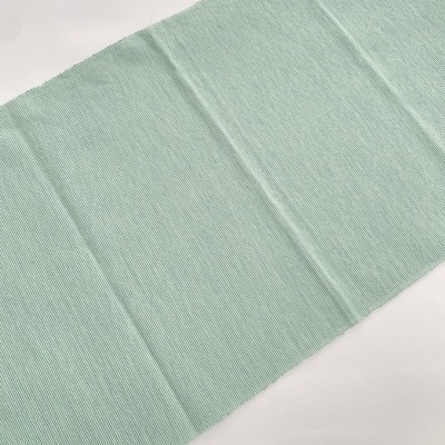 Tecido verde claro com textura de listras verticais sobre superfície branca
