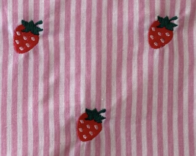 Tecido listrado rosa e branco com bordados de morangos vermelhos com folhas verdes
