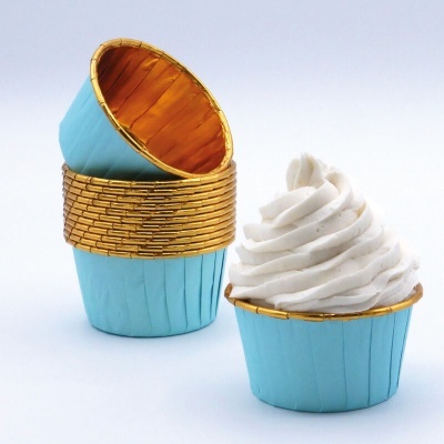 Forminhas de cupcake azuis com interior dourado e cupcake com cobertura branca