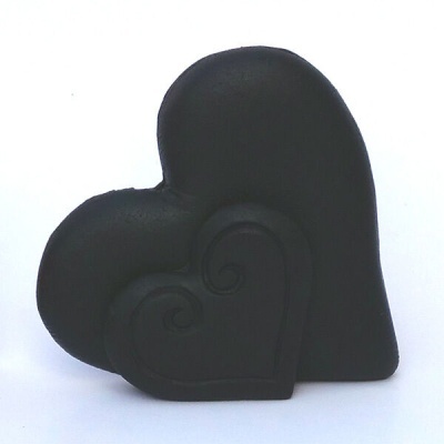 Dois corações de peluche preto com padrão em relevo sobre fundo branco.