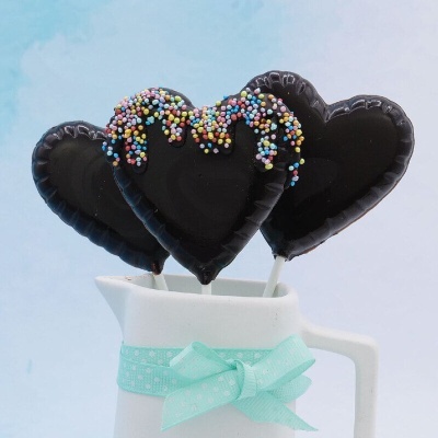 Pirulitos em forma de coração cobertos de chocolate num jarro branco com laço azul